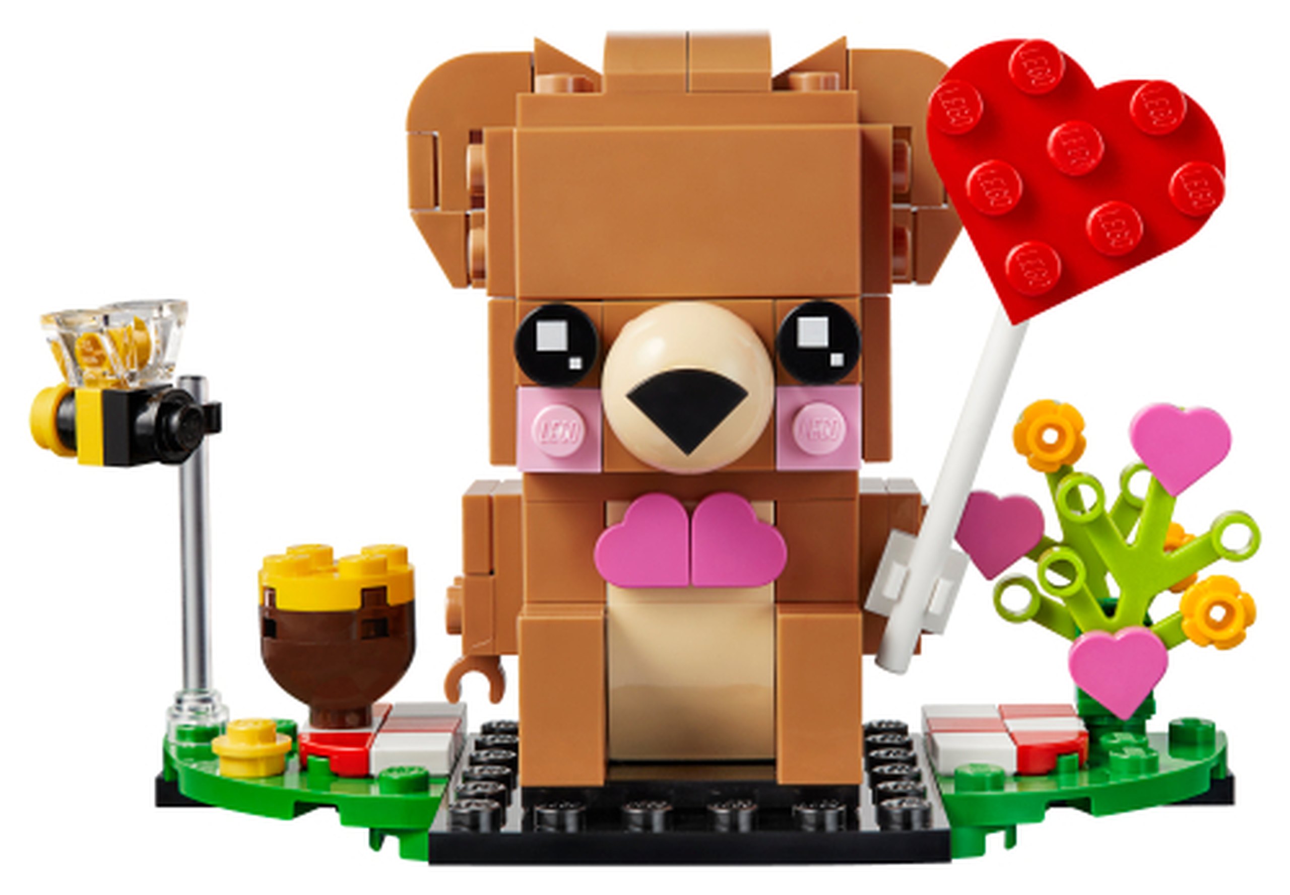 Modèle officiel LEGO 40379 : L’ours brun nougat moyen porte un nœud rose et un grand cœur rouge sur une tige blanche. Un pot de miel, une abeille et des fleurs complètent son socle.