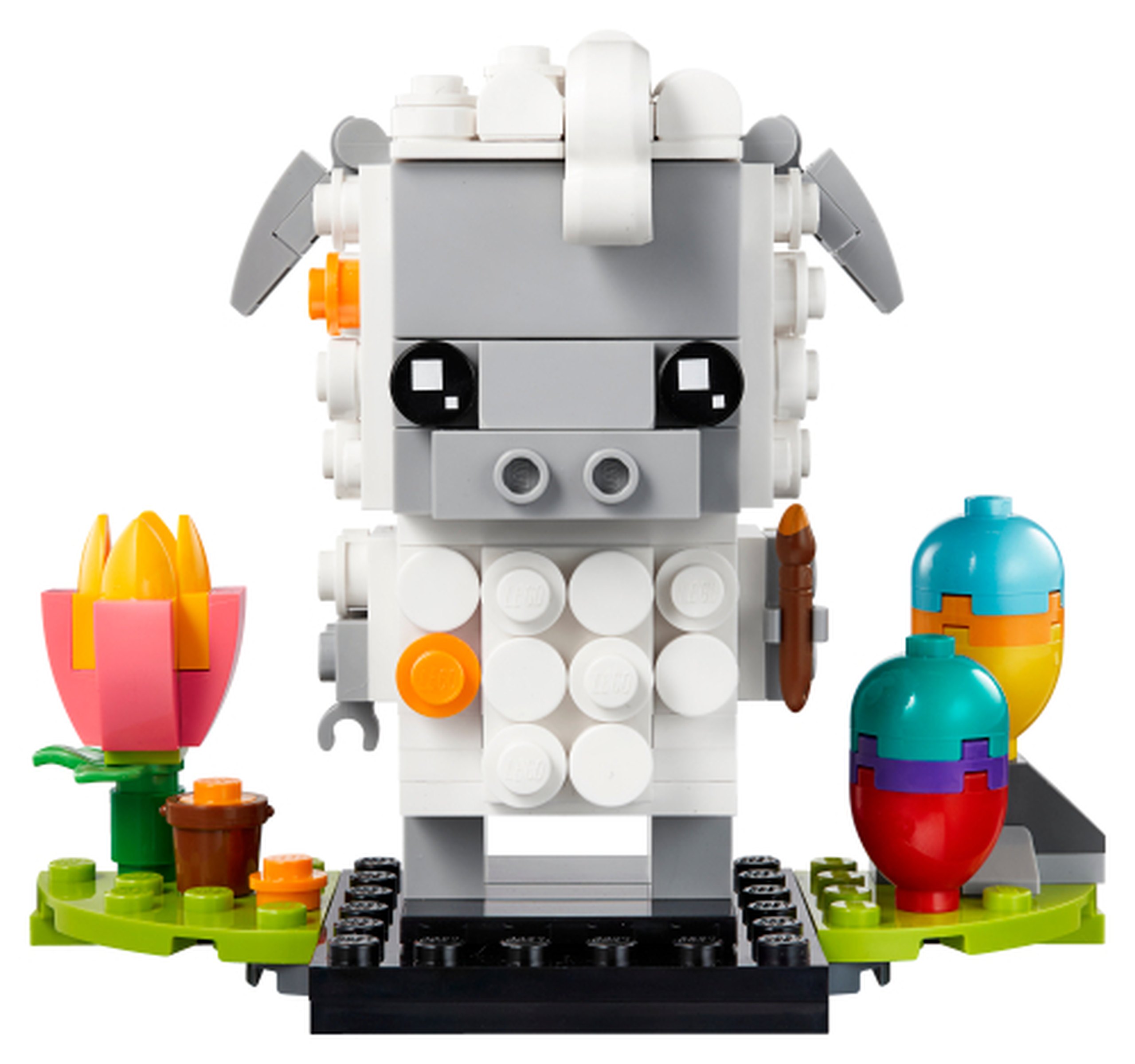 Modèle officiel LEGO 40380 : Le mouton présente une face grise et une laine blanche faite d’éléments ronds. Il tient un pinceau ; deux œufs colorés, une tulipe et un petit seau complètent le décor.