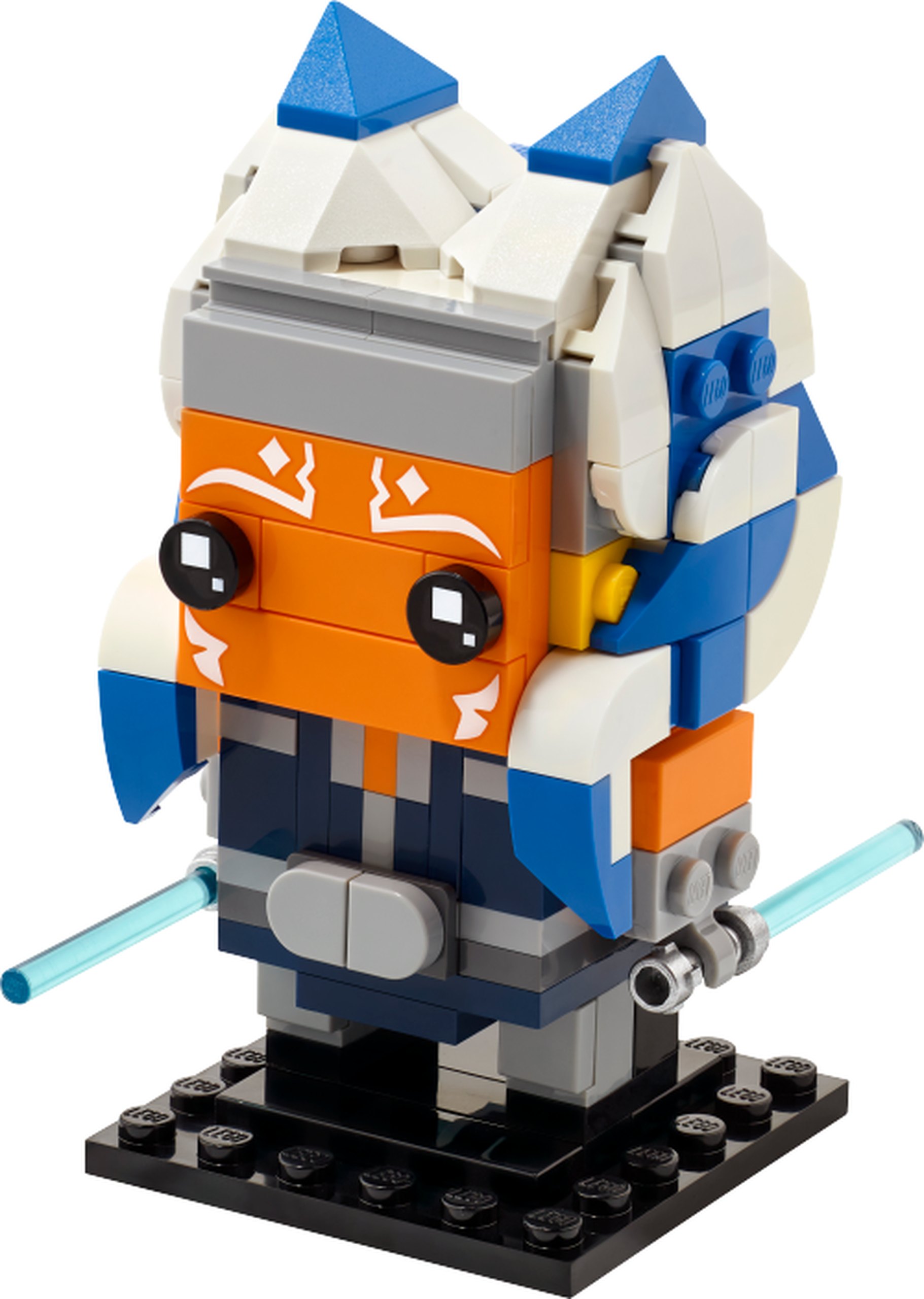 Modèle officiel LEGO 40539 : Le visage orange d’Ahsoka porte des marques blanches imprimées. Ses montrals et lekku alternent bleu et blanc ; sa tenue bleu foncé est complétée par une ceinture grise et deux sabres aux lames bleu clair transparent.