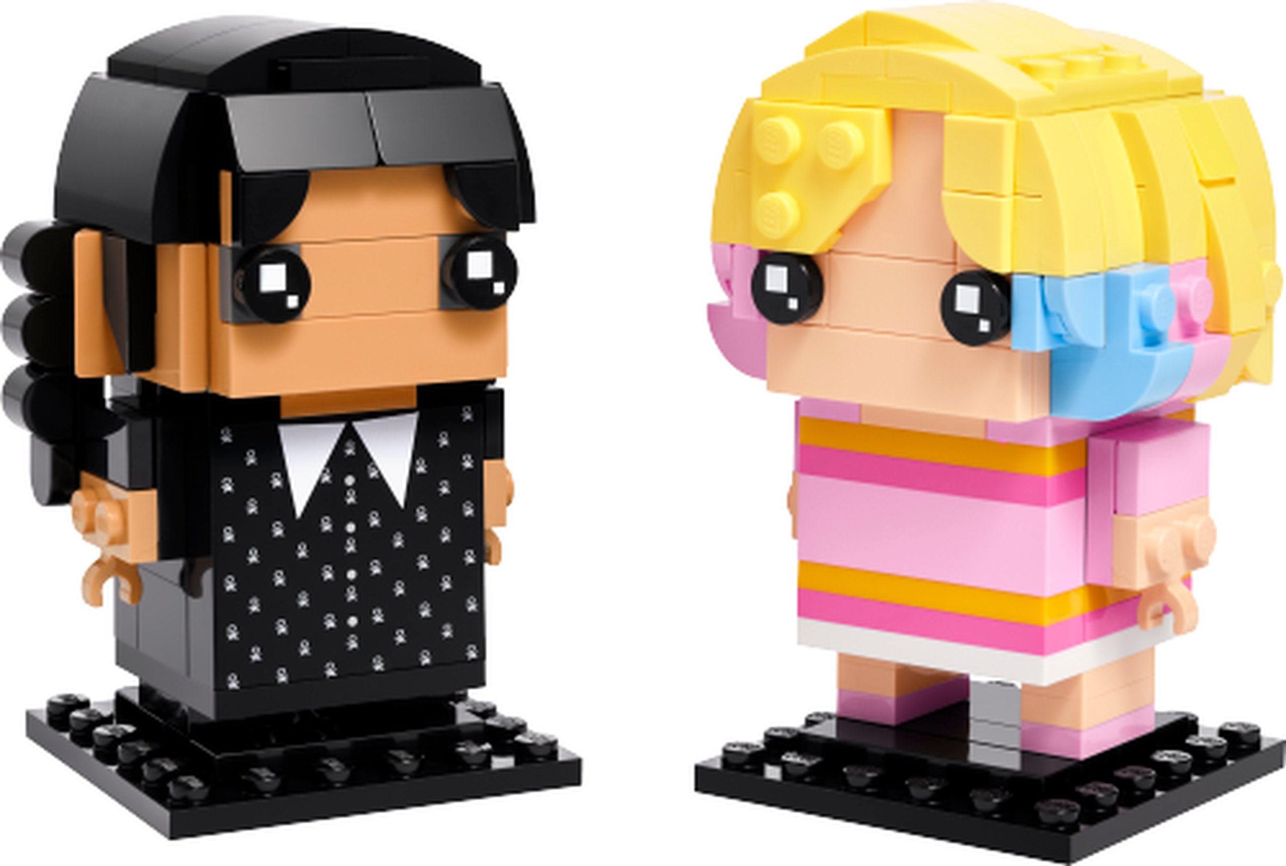 LEGO 40750 Mercredi et Enid : Mercredi porte une robe noire à col blanc et à petits motifs blancs, avec deux longues tresses noires. Enid associe une chevelure jaune clair à des extrémités roses et bleu clair, un pull rose rayé de jaune et une jupe claire. Les deux personnages ont des yeux BrickHeadz noirs et leur socle noir.