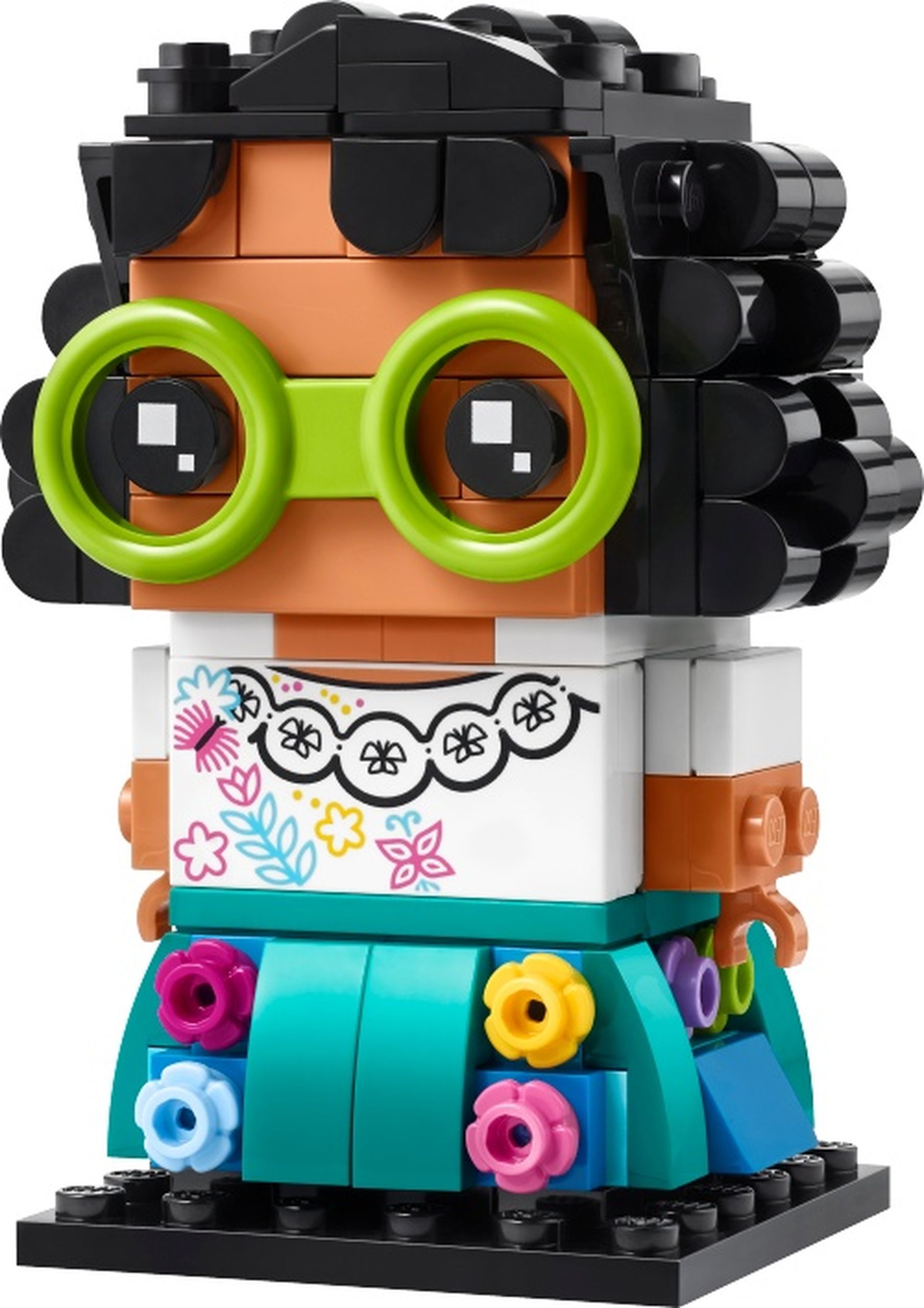 LEGO 40753 Mirabel Madrigal : Mirabel Madrigal porte de grandes lunettes rondes vert citron, des cheveux noirs bouclés et une blouse blanche imprimée de fleurs et de papillons. Sa jupe turquoise se décore de petites fleurs de plusieurs couleurs.
